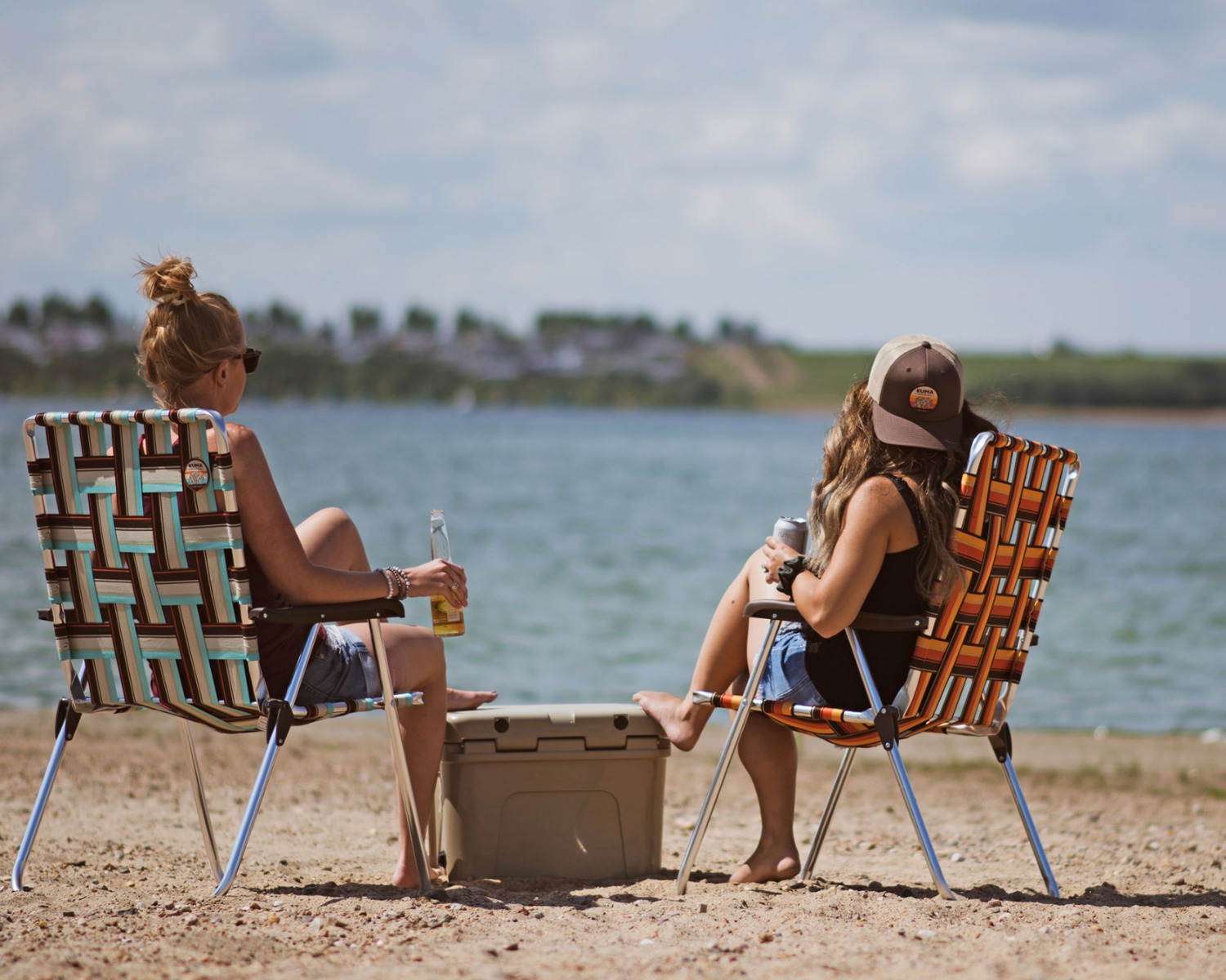 Two people sitting in Kuma Backtrack Chairs on a beach at a typical Alberta lake.